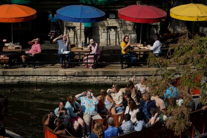 Diners along the Riverwalk and people on a river barge in San Antonio use special glasses to watch as the moon moves in front of the sun during an annular solar eclipse.