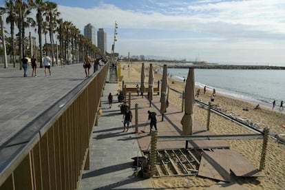 Operarios trabajan en la instalación de una terraza en la playa de la Barceloneta.