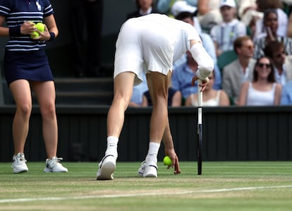 Jannik Sinner recoge el corcho que acabó en la pista durante el segundo set de la final de Wimbledon, este domingo.