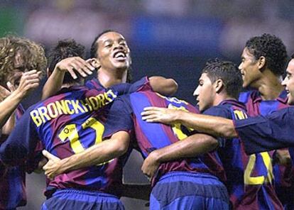 Ronaldinho y Van Bronckhorst se abrazan, junto a sus compañeros, en un partido de la pasada Liga.