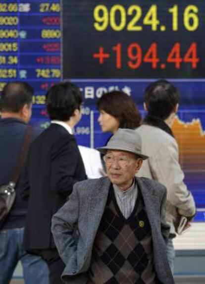 Varios viandantes caminan frente a una pantalla que muestra los valores bursátiles de la Bolsa de Tokio, en Tokio, Japón. EFE/Archivo