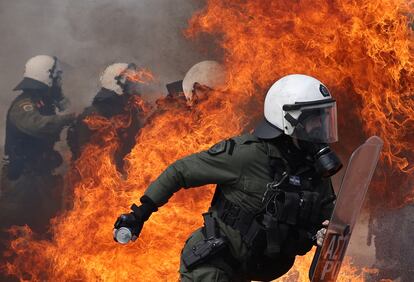 Un policía intenta escapar de las llamas de un 'cóctel molotov' lanzado por los manifestantes en Atenas, este jueves. 