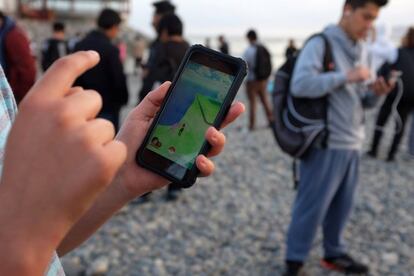 People walk with their mobile phones as some play Pokemon GO at La Punta beach in Callao, Peru, October 29, 2016. REUTERS/Mariana Bazo