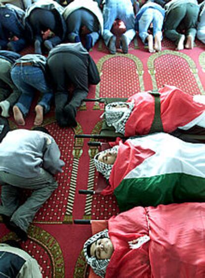 Palestinos rezan junto a los cuerpos de tres guardias de Arafat.