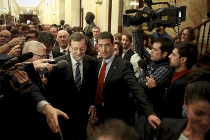 Responsables de seguridad ayudan a Mariano Rajoy a abrirse paso en el pasillo del Congreso entre los medios de comunicaci&oacute;n.