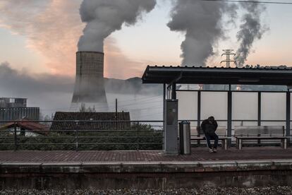 Las regiones carboníferas de España, situadas principalmente en Asturias y León, se enfrentan a un futuro incierto. En la imagen, un trabajador espera en la estación de tren de Las Segadas, con la central de energía térmica de Soto de Ribera de fondo, en Entrepuentes (Asturias),