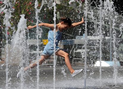 Un niño salta a través de unos chorros de agua en una calle comercial en Viena (Austria).