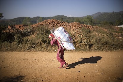 Una mujer trasporta un pesado saco por un camino de una zona rural a dos horas de Katmandú. Muchos hombres han emigrado al extranjero para buscar trabajos con los que poder mantener a sus familias. Ellas han asumido la batuta de sus hogares, haciéndose cargo de los hijos, los nietos, la labranza y el mantenimiento de las casas.