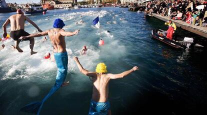 Los nadadores se arrojan al agua para la travesía del puerto.