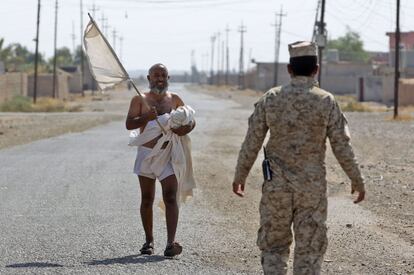Un hombre iraquí lleva su ropa en brazos según se acerca a las fuerzas militares iraquíes tras entrar en el pueblo de Shargat (Irak).