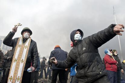 Un manifestante lanza una piedra a la policía antidisturbios, mientras que otro sostiene una cruz durante los enfrentamientos en la plaza de la Independencia de Kiev.















