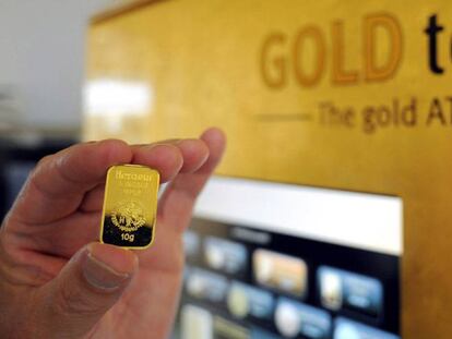 Un hombre sostiene una barra de oro de 10 gramos, despúes de la demostración de cómo se usa la máquina de venta de oro (