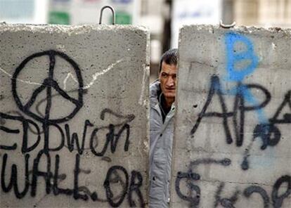 Un palestino mira a través de un hueco en el muro de separación israelí, ayer en Jerusalén.