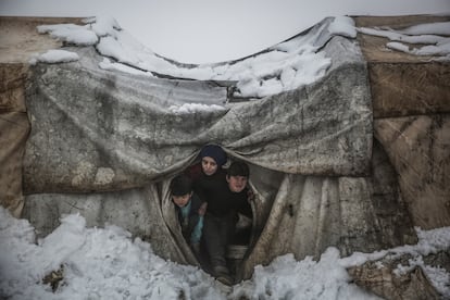 Unos niños sirios miran desde su tienda tras las fuertes nevadas en un campamento para desplazados internos cerca de la ciudad de Salqin, a finales de enero de 2022.