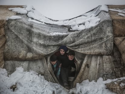 Unos niños sirios miran desde su tienda tras las fuertes nevadas en un campamento para desplazados internos cerca de la ciudad de Salqin, a finales de enero de 2022.