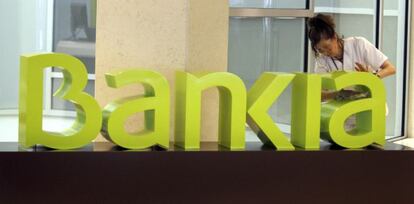 Una operaria limpia el logo de Bankia. 