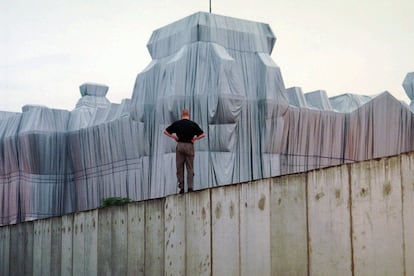 Un hombre sobre el Muro de Berlín contempla la obra de Christo en el Reichstag, en junio de 1995.