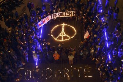 Gente reunida en Suiza con el símbolo de la paz (con la torre Eiffel) y el mensaje "Solidaridad" formado por velas.