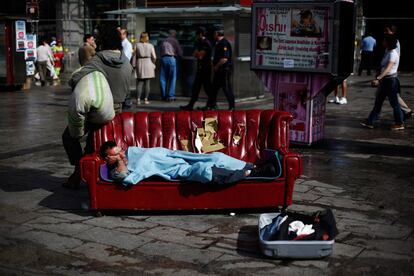 Un hombre duerme sobre un sofá colocado en la Puerta del Sol.