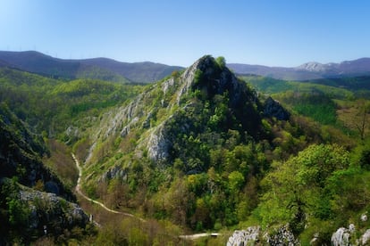 Cuenta la leyenda que por las cumbres del parque natural de Aizkorri-Aratz deambula la diosa vasca Mari, personificación de la madre tierra. En las 19.400 hectáreas de este entorno de sierras calizas y hayedos, entre las provincias de Álava y Gipuzkoa, nacen tres de los principales ríos de Gipuzkoa–el Deba, el Urola y el Oria– y se alza la cima más alta del País Vasco, el Aitxuri (1.551 metros). Su entrada principal se sitúa junto al Santuario de Arantzazu; la casa del parque, en la localidad alavesa de Araia, orienta sobre rutas, puntos de interés y visitas guiadas, y sirve de punto de partida para ascender al Aratz (1.443 metros). El centro de interpretación Aizkorriko Ataria, en el caserío Anduetza (en Zegama), descubre la cultura y la naturaleza de esta zona. En la imagen, el monte Aitzabal (Gipuzkoa). <br></br> Más información: <a href="https://turismo.euskadi.eus/es/espacios-naturales/parque-natural-de-aizkorri-aratz/aa30-12375/es/" target="_blank">turismo.euskadi.eus</a>