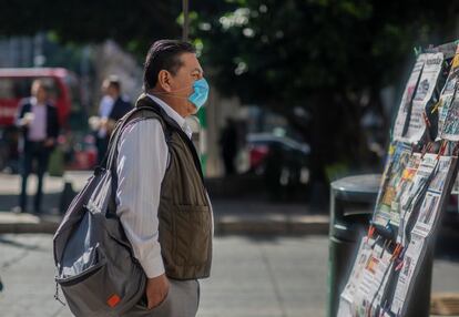 Un hombre, con un cubrebocas, mira los diarios en Ciudad de México.