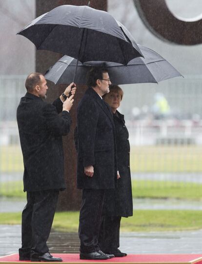 Angela Merkel, a la derecha y Mariano Rajoy, bajo los paraguas durante los honores militares.