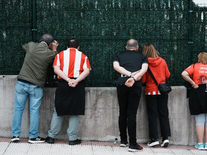 Unos aficionados observan desde una valla las instalaciones del Athletic de Bilbao, el viernes en Lezama (Bizkaia).