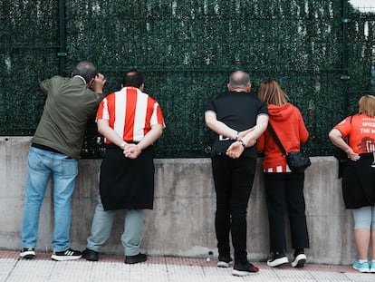 Unos aficionados observan desde una valla las instalaciones del Athletic de Bilbao, el viernes en Lezama (Bizkaia).