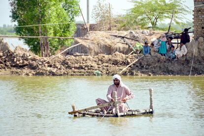 Un hombre afectado por las inundaciones utiliza una balsa improvisada para cruzar una corriente de agua cerca de su casa dañada en Jaffarabad, provincia de Baluchistán, en Pakistán, el 23 de septiembre de 2022.