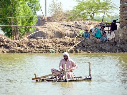 Un hombre afectado por las inundaciones utiliza una balsa improvisada para cruzar una corriente de agua cerca de su casa dañada en Jaffarabad, provincia de Baluchistán, en Pakistán, el 23 de septiembre de 2022.