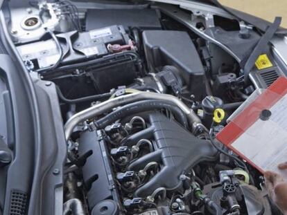 Un operario analiza una el motor de un coche para su reparación.