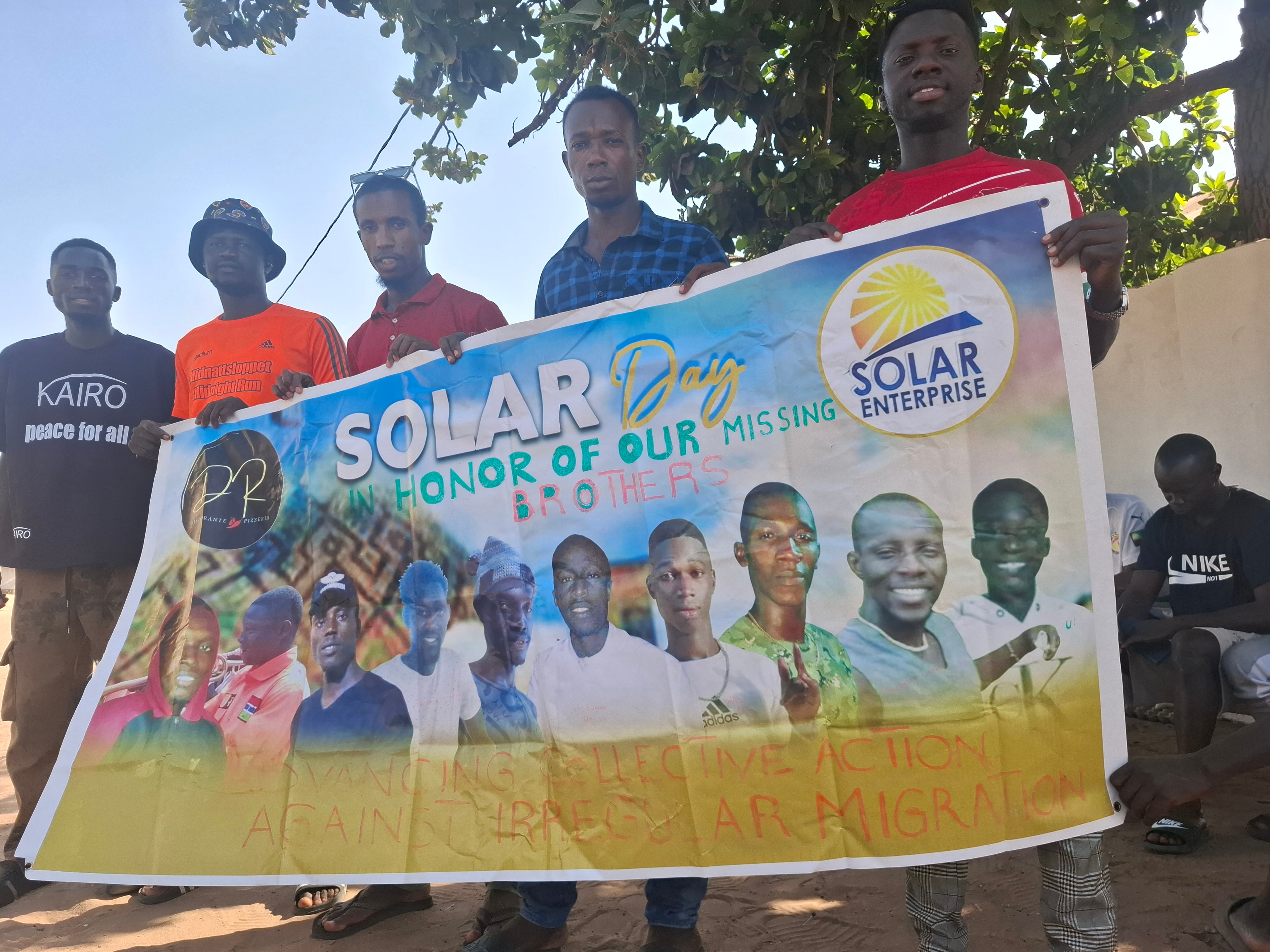 Jóvenes del equipo de fútbol Solar Enterprise sostienen una pancarta con las imágenes de sus compañeros desaparecidos en la emigración hacia Canarias.