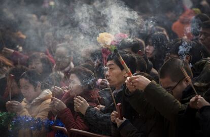 Un grupo de chinos sujeta barras de incienso mientras rezan durante la celebración del comienzo del Nuevo Año chino en el templo de Yonghegong en Pekín, China.