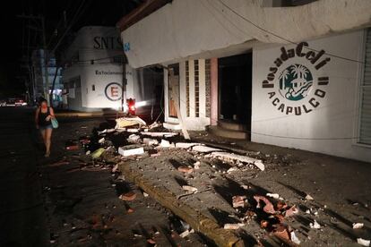 Una mujer camina frente a los destrozos ocasionados por el seísmo en un negocio en Acapulco.