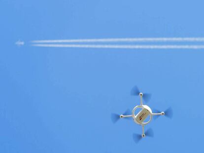 Un dron vola sota el rastre d'un avió comercial.