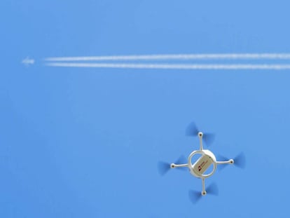 Un dron vuela bajo la estela de un avi&oacute;n comercial.