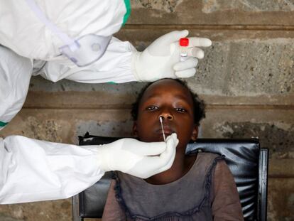 Un sanitario realiza una PCR a una niña durante una prueba masiva en un barrio marginal de Kibera en Nairobi (Kenia).