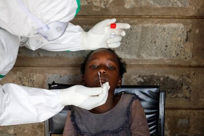 Un sanitario realiza una PCR a una niña durante una prueba masiva en un barrio marginal de Kibera en Nairobi (Kenia).