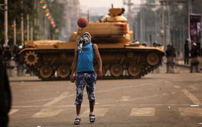 Un opositor juega al f&uacute;tbol frente a un tanque desplegado ante el palacio presidencial en El Cairo.