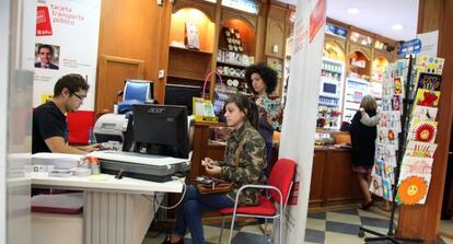 Jóvenes se hacen el abono transporte en un estanco de Madrid.