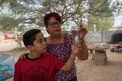 Marisol y su hijo, habitantes de Bacanuchi, observan un vaso de agua corriente, que no pueden beber desde el derrame de 2014.