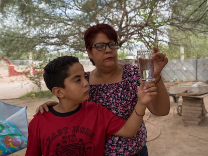 Marisol y su hijo, habitantes de Bacanuchi, observan un vaso de agua corriente, que no pueden beber desde el derrame de 2014.