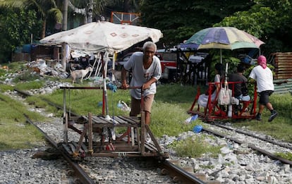 Dos filipinos utilizan carros improvisados para transportar a los viajeros por las vías del tren, en Manila (Filipinas).