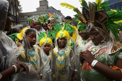 Asistentes al carnaval se resguardan de la lluvia, cerca de Ladbroke Grove.