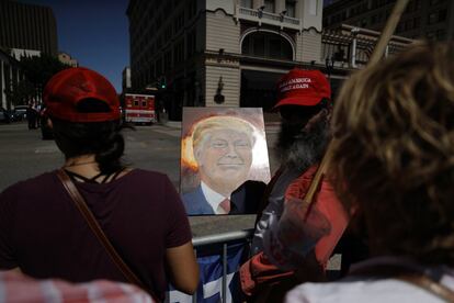 Un hombre sostiene un retrato de Donald Trump mientras espera con otros partidarios la llegada del presidente a una recaudación de fondos en San Diego.