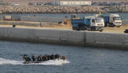 Una zodiac militar pasa frente a las obras del nuevo muelle en la base naval de Rota (Cádiz).
