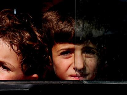 Dos niños sirios llegan en autobús al campo de refugiados de la Media Luna Roja instalado en Altinozu, a 30 kilómetros de la frontera entre Siria y Turquía.