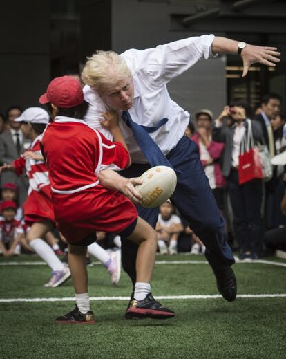 Na imagem, o primeiro-ministro dribla um garoto jogando rugby em um torneio nas ruas de Tóquio em 2015.