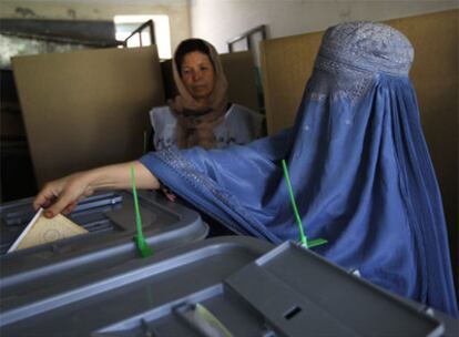 Una mujer afgana vestida con una <i>burka</i> deposita su voto en la urna en un colegio de Kabul.