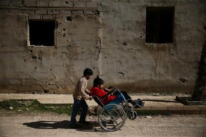 Ziad (derecha), de 14 años, es empujado en su silla de ruedas por un amigo a través de las calles de Douma, el principal bastión rebelde a las afueras de Damasco (Siria).